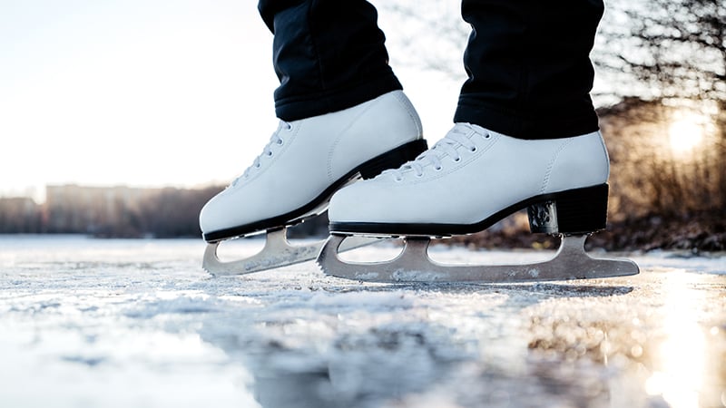 Eislaufen Nahaufnahme von weißen Schlittschuhen auf natürlichem Eis bei Sonnenuntergang.